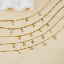 Load image into Gallery viewer, Several gold letter charm necklaces with custom names on a cream background