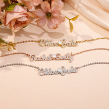 Load image into Gallery viewer, Iced out name necklaces in 18K gold, rose gold and silver plating laid on pink flowers