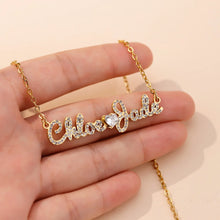 Load image into Gallery viewer, Hand holding a gold Chloe and Jade iced out name necklace to show the pendant size