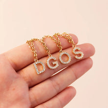 Load image into Gallery viewer, Gold CZ letter charms D, G, O and S held in a hand to show their size