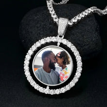 Load image into Gallery viewer, Silver color rotating pendant on a CZ chain resting on a black stone, dark background
