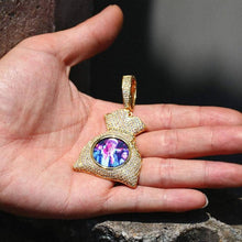 Load image into Gallery viewer, A hand holding the 14k yellow gold iced-out money bag custom picture pendant, showing its premium size and detailed 5A zircon stones.