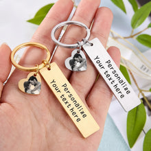 Load image into Gallery viewer, Gold and silver heart photo keychains with black and white pictures and engraved text bars, held in hand