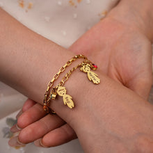 Load image into Gallery viewer, Hand holding a gold kids name charm bracelet with birthstones at the wrist