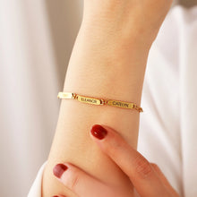 Load image into Gallery viewer, Woman wearing a gold paperclip name bracelet with engraved name bars