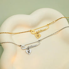 Load image into Gallery viewer, Gold and silver custom safety pin necklaces with heart initial charms on a white dish