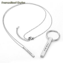 Load image into Gallery viewer, Engraved vertical bar pendant resting on stone surface in natural light